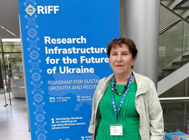 Оксана Столяр біля офіційного банера саміту